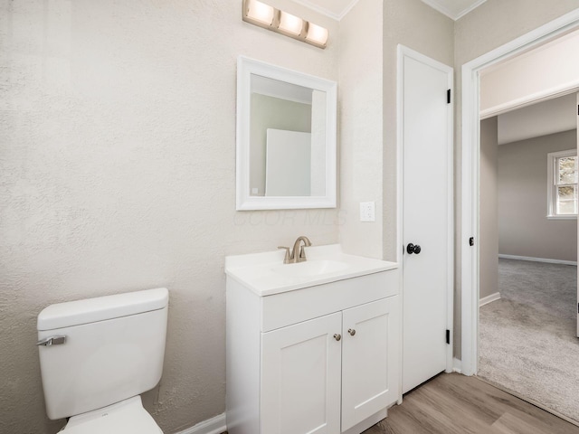 bathroom with toilet, hardwood / wood-style flooring, crown molding, and vanity