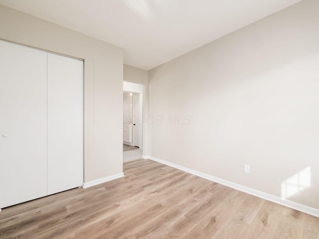 unfurnished bedroom with a closet and light hardwood / wood-style floors