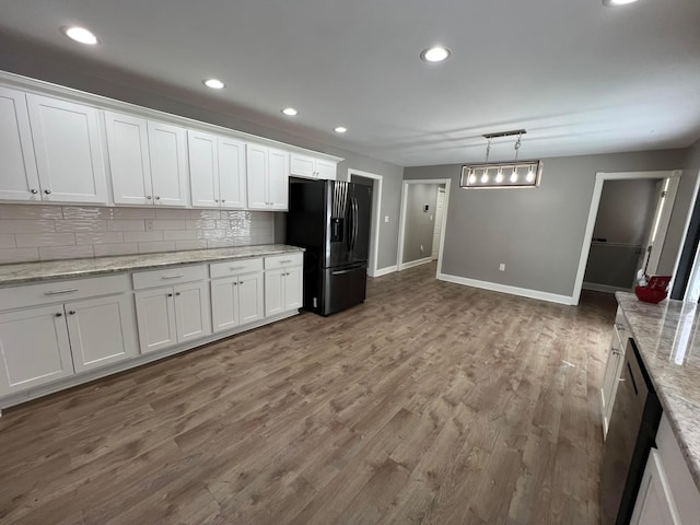 kitchen with light stone countertops, white cabinetry, backsplash, and black refrigerator with ice dispenser