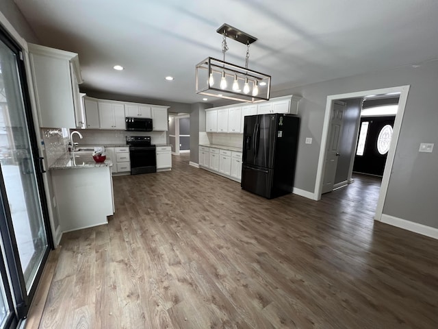 kitchen with decorative backsplash, hanging light fixtures, white cabinets, and black appliances