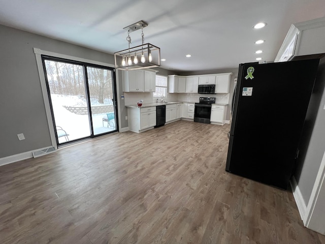 kitchen featuring backsplash, sink, black appliances, white cabinetry, and hanging light fixtures