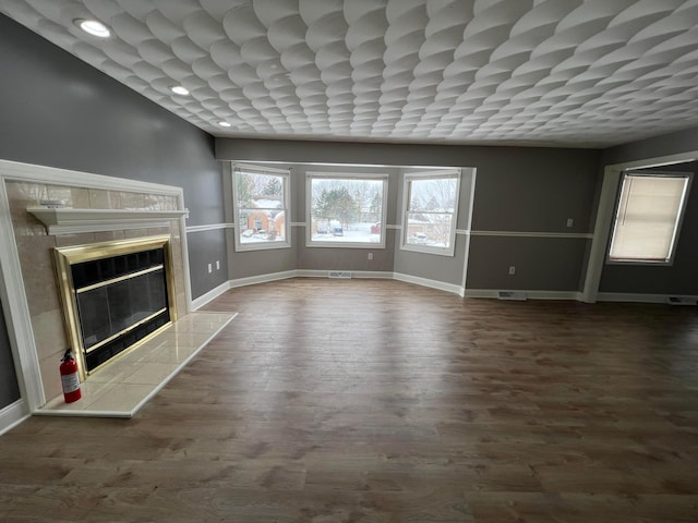 unfurnished living room with a tile fireplace and dark hardwood / wood-style floors