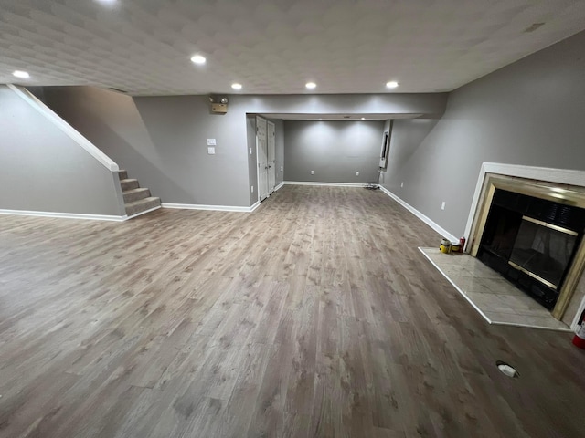 unfurnished living room with a tile fireplace and hardwood / wood-style floors