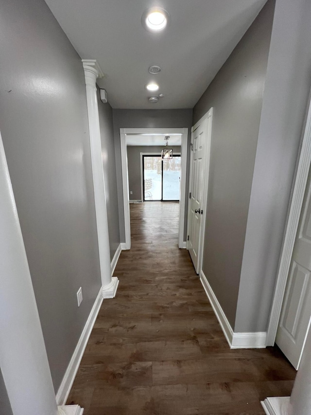 corridor with a chandelier, dark hardwood / wood-style floors, and decorative columns