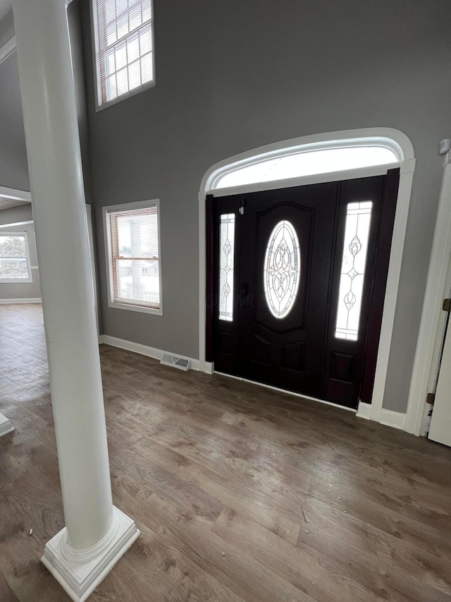 foyer entrance featuring decorative columns, hardwood / wood-style floors, and a high ceiling