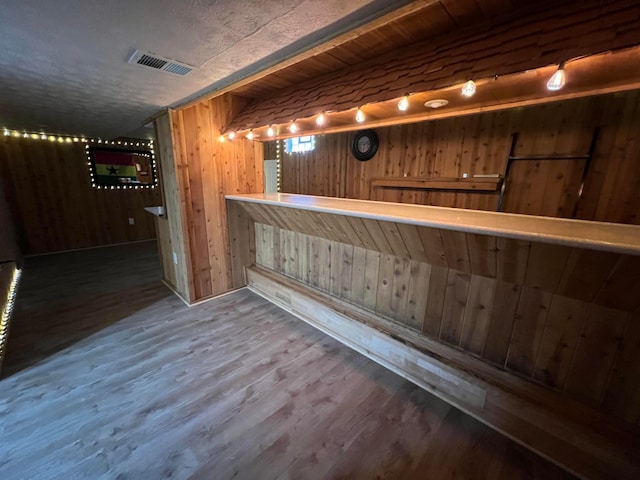 bar featuring hardwood / wood-style flooring and wood walls