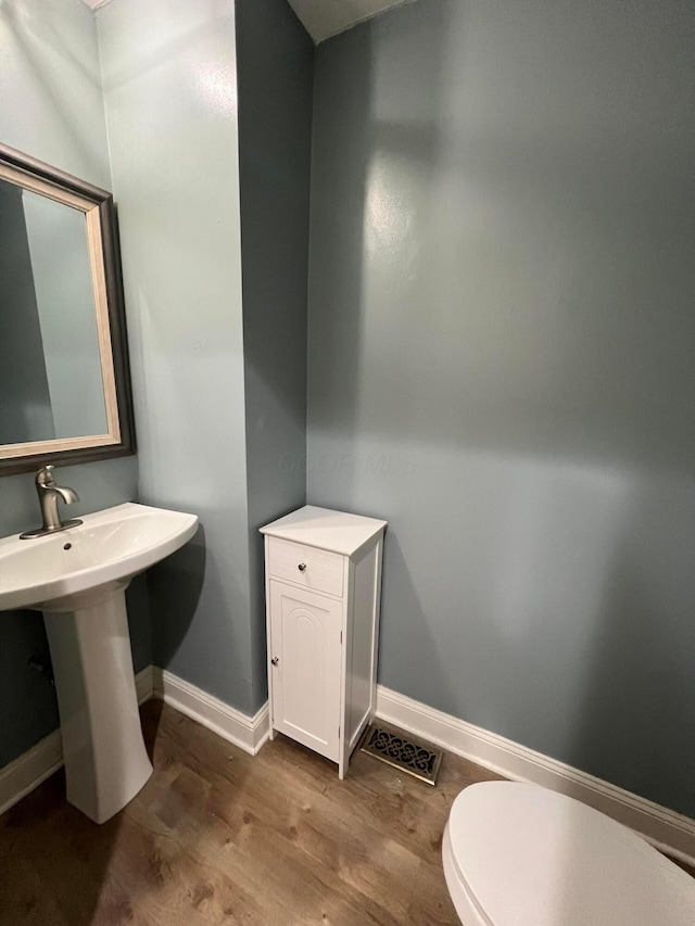 bathroom with hardwood / wood-style flooring, toilet, and sink