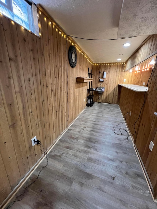 corridor featuring wooden walls, hardwood / wood-style floors, and a textured ceiling