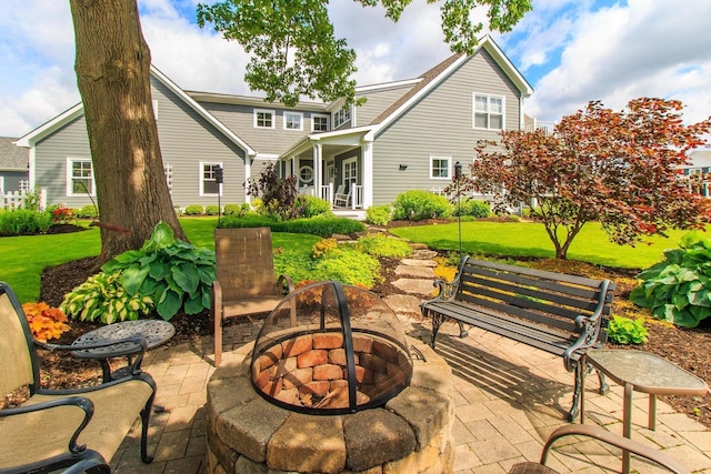 rear view of property featuring a patio area, a yard, and a fire pit