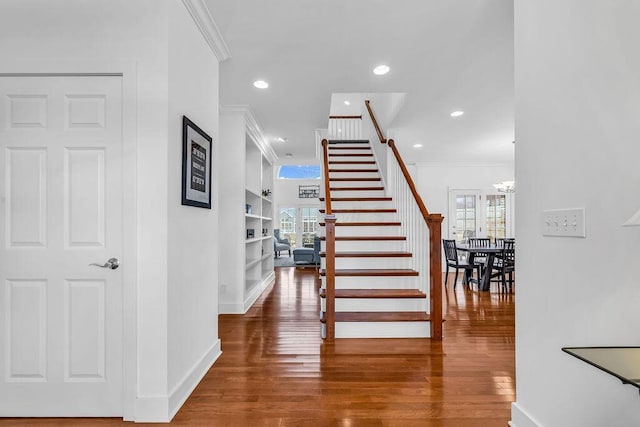 stairs with built in shelves, hardwood / wood-style flooring, and ornamental molding