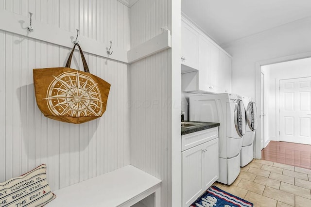 laundry area with washer and dryer, light tile patterned flooring, and cabinets