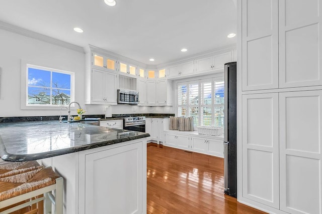 kitchen featuring kitchen peninsula, appliances with stainless steel finishes, a breakfast bar, sink, and white cabinets