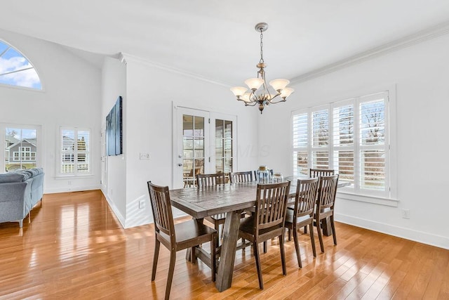 dining space featuring wood-type flooring, ornamental molding, and an inviting chandelier