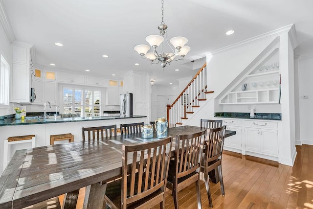 dining space featuring light wood-type flooring, ornamental molding, sink, and a chandelier