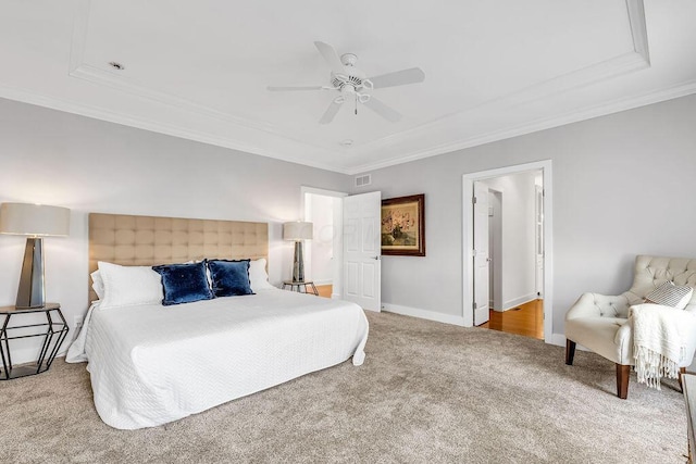 carpeted bedroom with a raised ceiling, ceiling fan, and ornamental molding