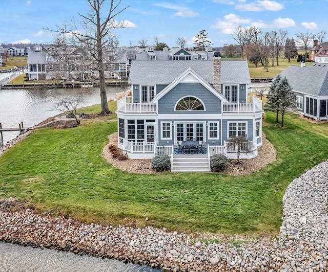 rear view of house featuring a deck with water view, a yard, and french doors