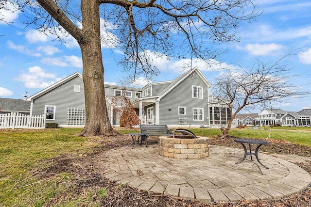 rear view of property with a fire pit, a patio area, and a yard