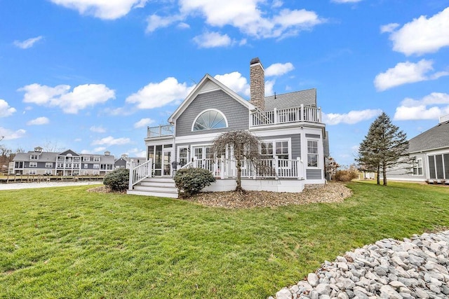 rear view of property featuring a yard and a balcony