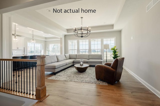 living room with hardwood / wood-style flooring, a chandelier, and a tray ceiling