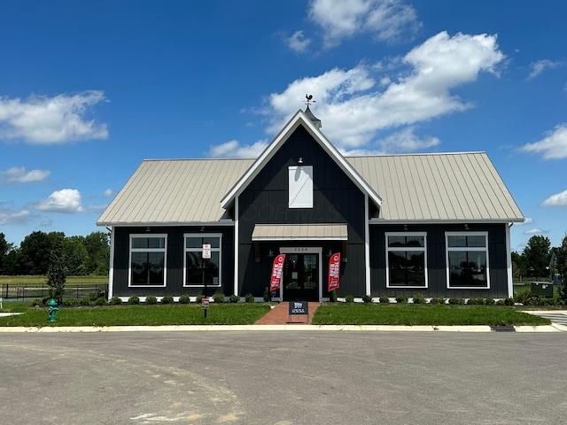 view of front facade featuring metal roof, a standing seam roof, board and batten siding, and fence