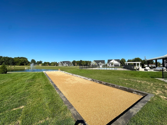 view of home's community with a water view, fence, and a lawn