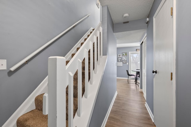 stairway featuring a textured ceiling and hardwood / wood-style flooring