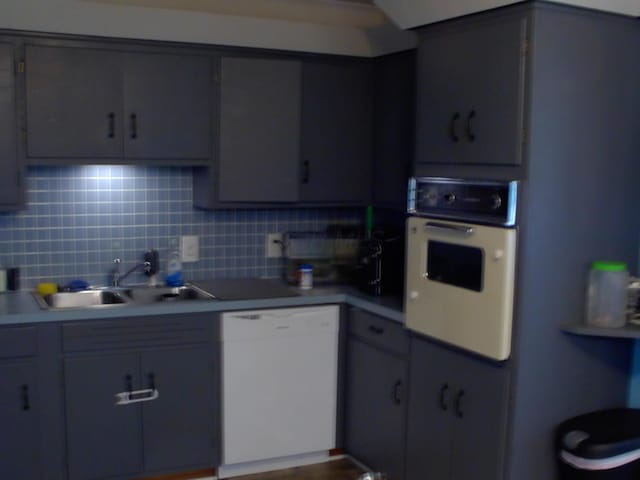 kitchen with white appliances, tasteful backsplash, gray cabinetry, and sink