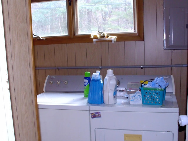 laundry area featuring electric panel, wooden walls, and independent washer and dryer