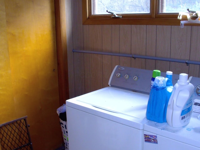 clothes washing area with wooden walls and washing machine and clothes dryer