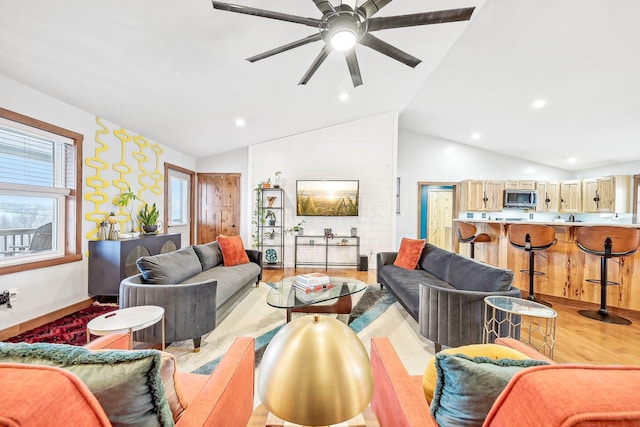 living room with ceiling fan, high vaulted ceiling, and light hardwood / wood-style floors