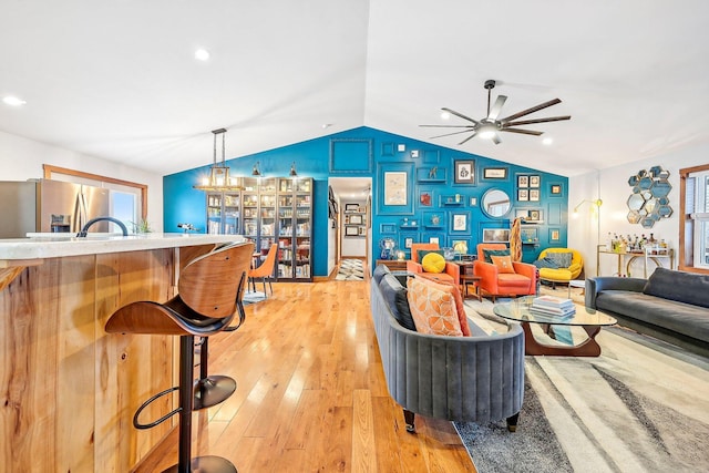 living room featuring ceiling fan, light hardwood / wood-style floors, and lofted ceiling