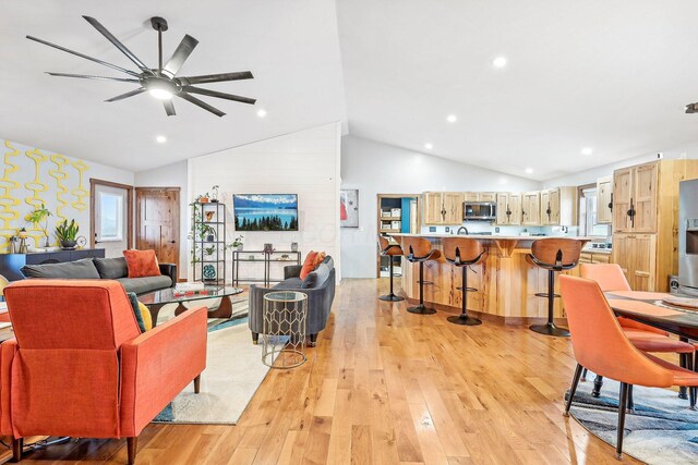 living room with high vaulted ceiling, light hardwood / wood-style flooring, ceiling fan, and a healthy amount of sunlight