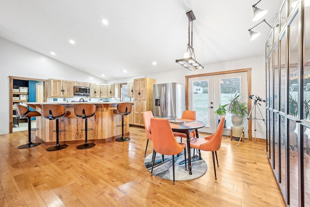 dining room featuring lofted ceiling, light hardwood / wood-style flooring, and french doors