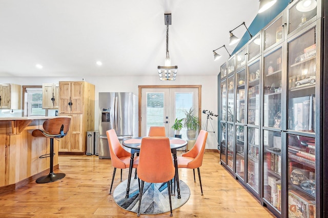 dining area with a healthy amount of sunlight, light wood-type flooring, and french doors