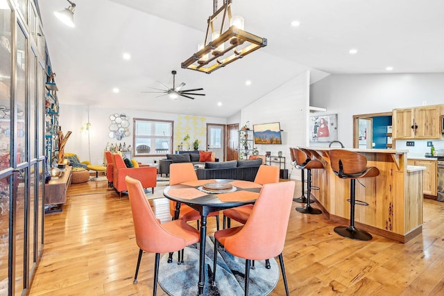 dining space with ceiling fan, high vaulted ceiling, and light hardwood / wood-style floors