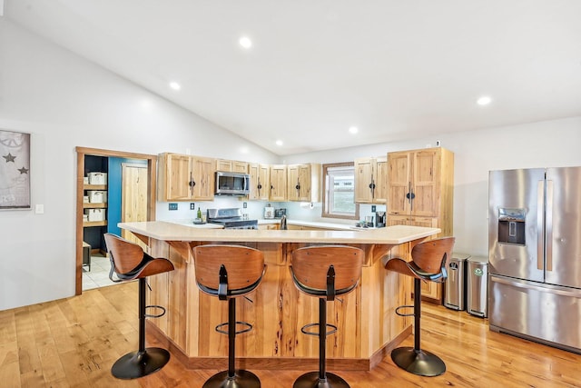 kitchen featuring a center island, lofted ceiling, stainless steel appliances, and light hardwood / wood-style flooring