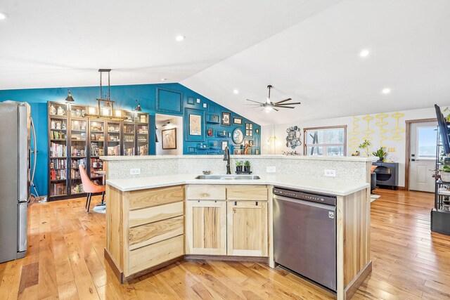 kitchen with appliances with stainless steel finishes, light wood-type flooring, light brown cabinetry, vaulted ceiling, and sink