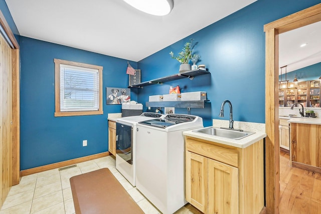 clothes washing area featuring cabinets, washing machine and dryer, light tile patterned flooring, and sink