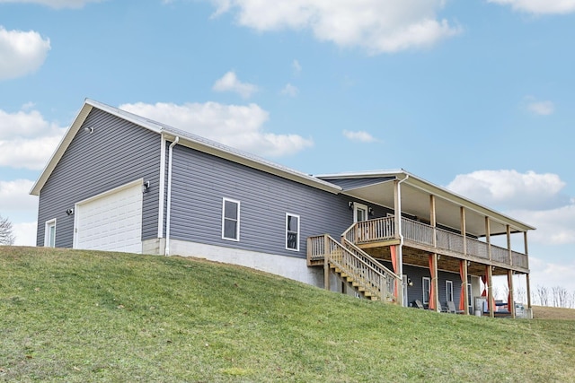 rear view of property with a lawn, a wooden deck, and a garage