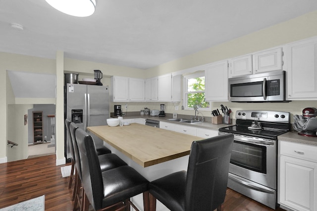 kitchen featuring white cabinets, a kitchen bar, stainless steel appliances, and sink