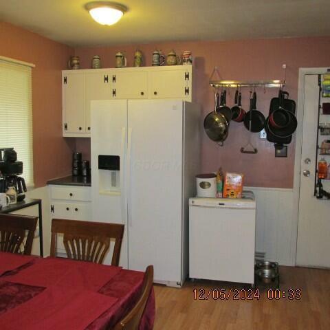 kitchen with white cabinetry, light wood-type flooring, white refrigerator with ice dispenser, and fridge