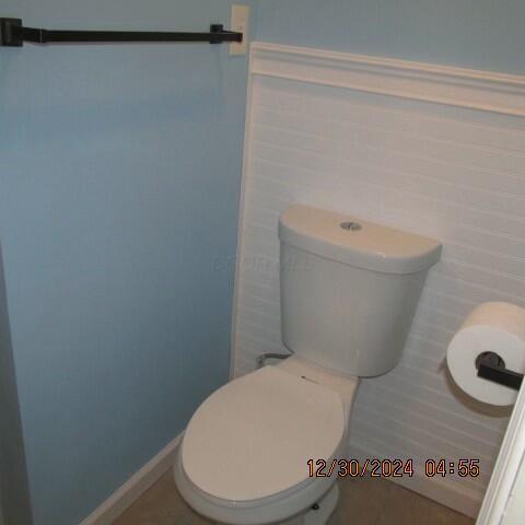 bathroom featuring toilet and tile walls