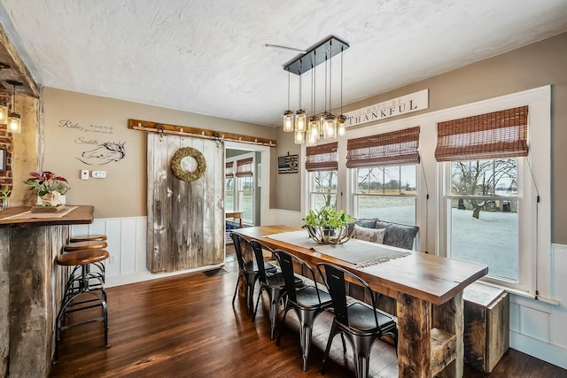 dining space with a barn door, a water view, and dark wood-type flooring