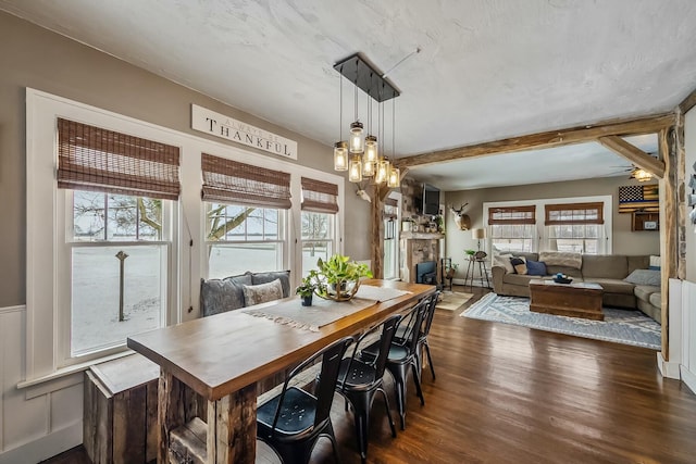 dining room featuring dark hardwood / wood-style floors, a stone fireplace, a wealth of natural light, and a notable chandelier