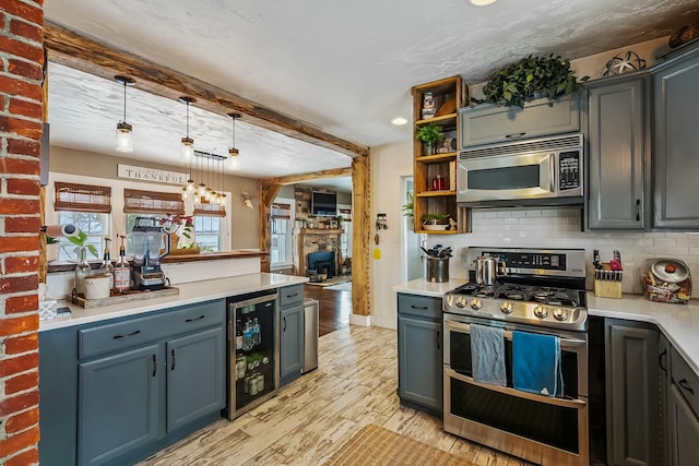 kitchen with pendant lighting, tasteful backsplash, light hardwood / wood-style floors, stainless steel appliances, and beverage cooler