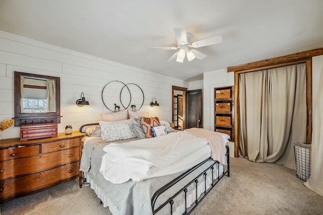 carpeted bedroom featuring ceiling fan and wooden walls