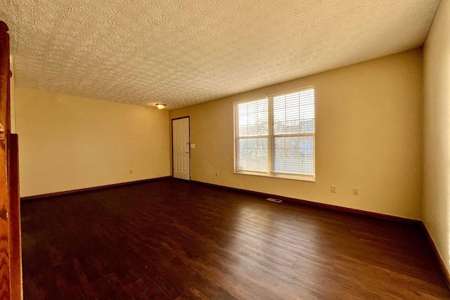 empty room featuring dark hardwood / wood-style floors and a textured ceiling