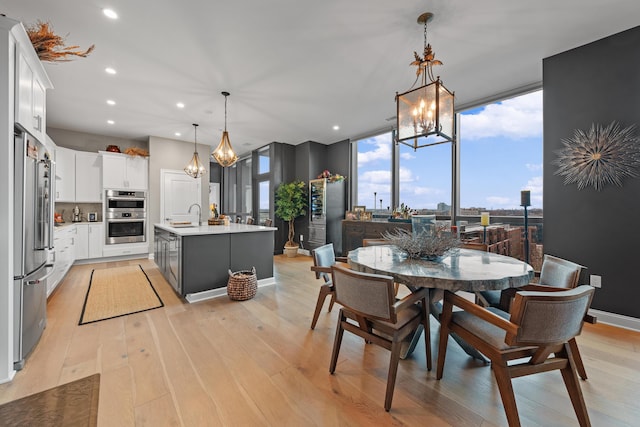 dining space featuring floor to ceiling windows, light hardwood / wood-style floors, and sink