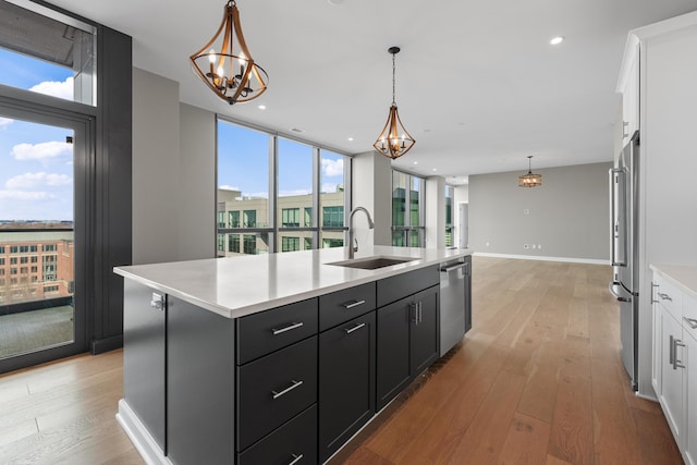 kitchen featuring white cabinets, a sink, light countertops, light wood-type flooring, and stainless steel dishwasher