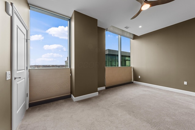 spare room featuring carpet floors, visible vents, baseboards, and a ceiling fan